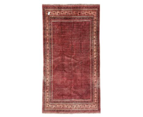 Persian Arak crimson ground rug, the field decorated with repeating Boteh motifs within geometric guard stripesDimensions: Le