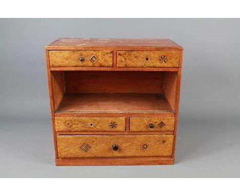 A Miniature Inlaid Chest. The chest having one long and four short drawers with an open shelf, possibly an apprentice's piece