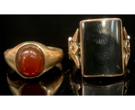A 9ct rose gold ring, set with black onyx, size Q, unmarked, 6.6g; a 9ct gold ring, set with a single polishe carnelian caboc