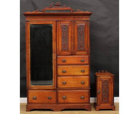 A late Victorian wardrobe, outswept cornice with shaped pediment above a mirrored door neighboured by carved panel doors and 