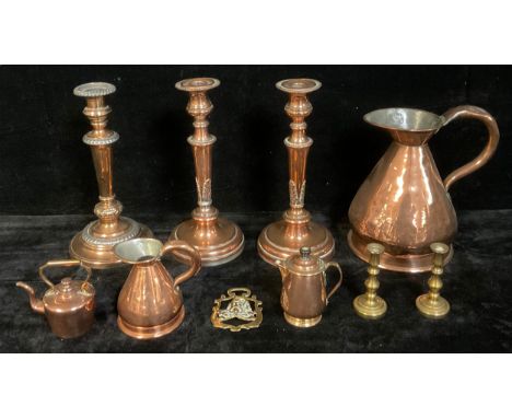 A 19th century copper flagon, 23cm; a pair of copper candlesticks gadrooned spreading circular sconces, the supports cast wit