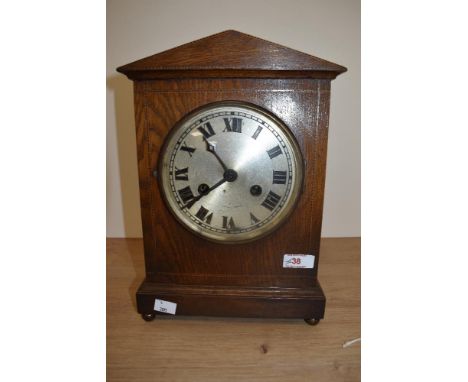 An Edwardian oak cased mantel clock having silvered roman numeral dial