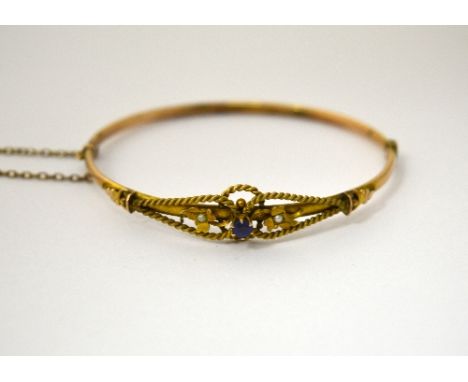 AN EDWARDIAN BANGLE, with central blue paste stone, rope twist sides and split pearl foliage detail, stamped 9ct