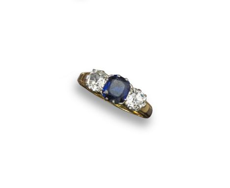 A sapphire and diamond three stone ring, the emerald-cut sapphire is set between two old cushion-shaped diamonds in platinum 