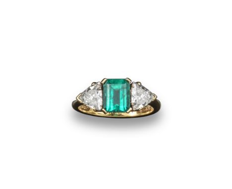 An emerald and diamond three stone ring, the emerald cut emerald is set with a trillion cut diamond to each shoulder in 18ct 