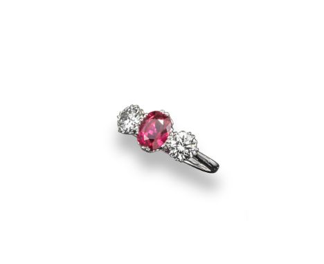 A ruby and diamond three stone ring, the oval-shaped ruby is set with two round brilliant-cut shoulder diamonds in platinum. 