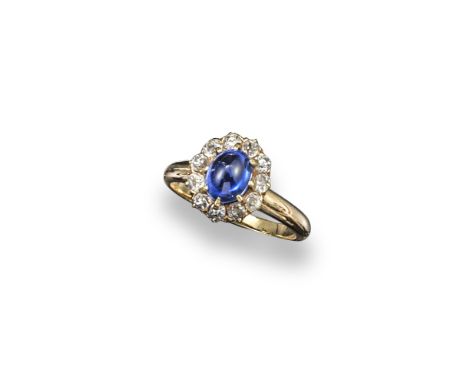 A sapphire and diamond set cluster ring, the oval-shaped sapphire cabochon is set within a surround of cushion-shaped diamond