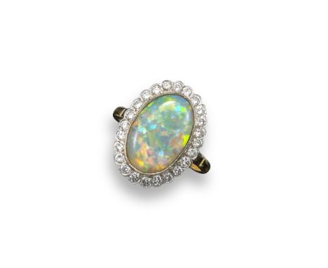 An opal and diamond cluster ring, the solid white opal cabochon is millegrain-set within a surround of circular-cut diamonds 