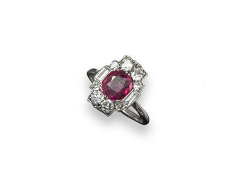 An Art Deco ruby and diamond cluster ring, the oval shaped ruby is set with two baguette-shaped shoulder diamonds and eight g