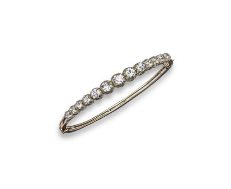 A late Victorian diamond-set hinged bangle, the graduated old circular-cut diamonds are each set in cut down silver collets a