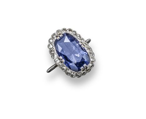A cushion-shaped sapphire and diamond cluster ring, the sapphire is set within a surround of single-cut diamonds in white gol