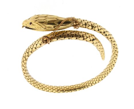 A gold snake bangle, the stylised serpent has a flexible, articulated body, and with rubies set to the eyes, in yellow gold. 