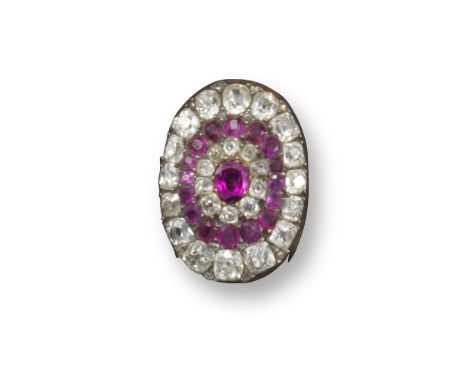 An early twentieth century ruby and diamond cluster clip brooch, centred with an oval-shaped ruby (chipped)  set within a sur