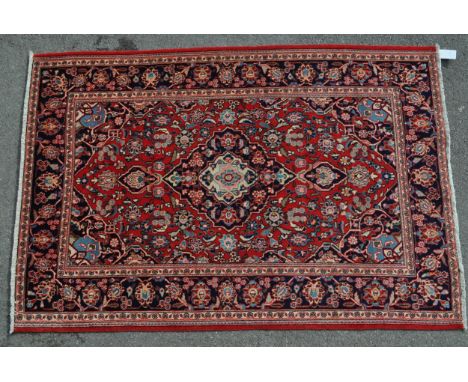 A 20th century central Persian kashan floor rug carpet. Having a red ground with a large black central medallion,&nbsp;surrou