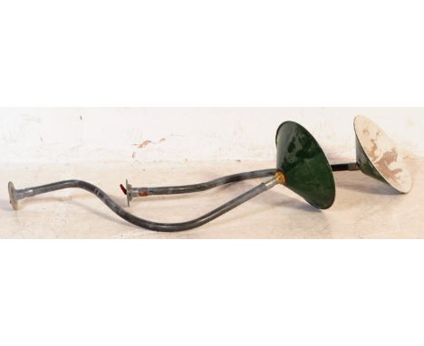 A pair of Industrial mid century yard lamps. Each on tubular metal swan neck wall mounts having green and white enamel UFO st