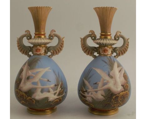 A pair of Royal Worcester vases, decorated with flying swans to a powder blue ground, by C H C Baldwyn, with open dolphin han
