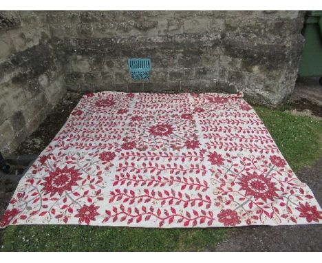 An embroidered bed spread, with red foliate decoration, 101ins x 101ins