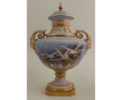 A Royal Worcester covered pedestal vase, decorated with flying swans by C H C Baldwyn, on a powder blue ground, with gilt and