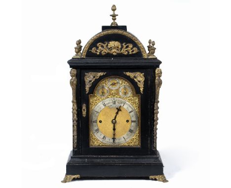 A VICTORIAN BRACKET CLOCK with arching ebonised case, decorated with gilt metal mounts and urn finials, and standing on cast 