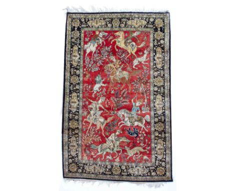 A  PERSIAN STYLE SILK RED GROUND RUG depicting hunting characters on horseback, and having a banded border with bird and flow