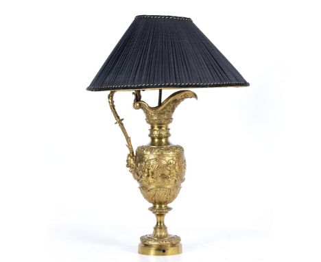 A TABLE LAMP constructed from a gilt cast metal ewer of classical form decorated with putti and bands of fruiting vine, the e