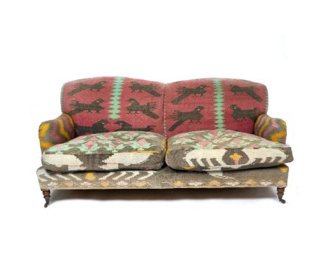 A HOWARD STYLE TWO SEATER SOFA in the manner of Paul Smith, with turned front legs and casters, upholstered in geometric desi