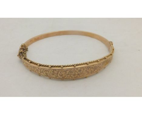 A 9 carat gold bangle with floral decoration