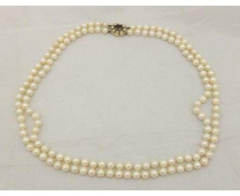 A twin strand pearl necklace with 9 carat gold clasp set with further pearls and a ruby