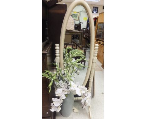 A brass framed floor standing shaving mirror, a brassed adjustable standard lamp with cream shade, a cream painted oval cheva