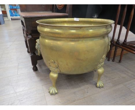 A late 19th early 20th Century brass jardiniere / log box with lion mask ring drop handles raised on four paw feet, discolour