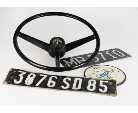  Motoring, a vintage three spoke steering wheel, together with a circular  cast metal Michelin advertising sign, 18cm diamete