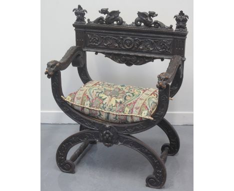 VICTORIAN CARVED AND STAINED SAVONAROLA TYPE ELBOW CHAIR, overall decorated with foliate scrolls, dragons and masks and havin