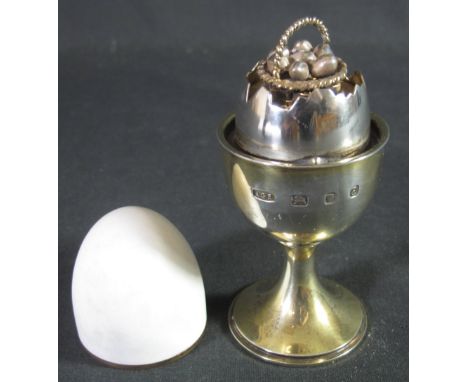 ELIZABETH II SILVER GILT AND EGGSHELL ENAMEL EGG AND EGG CUP BY ANTHONY ELSON, containing a  basket of 'surprise' basket of e