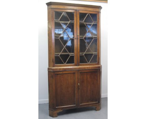 EARLY 19TH CENTURY WELSH OAK DOUBLE CORNER CABINET, having moulded and geometrically inlaid frieze above two astragal glazed 