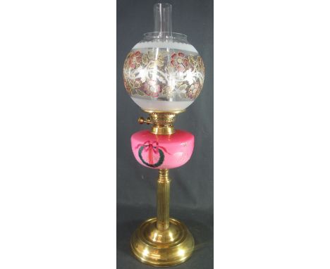 EARLY 20TH CENTURY BRASS DOUBLE BURNER OIL LAMP with pink ceramic reservoir, having painted enamel decoration on a reeded col