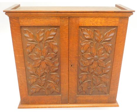 An early 20thC oak small cabinet, with moulded corners, above two floral carved doors, including a fitted interior, with draw