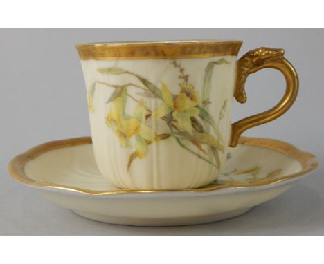 A Royal Worcester porcelain cup and saucer, painted with daffodils and other flowers, on a blush ivory ground, within a gilt 