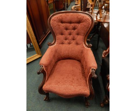 A Victorian mahogany show-frame armchair, with a padded back, armrests and seat, scroll carved supports and ceramic castors