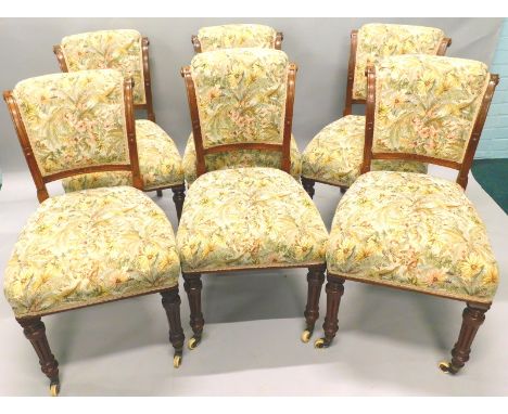 A set of six Victorian walnut dining chairs, each with a later upholstered padded back and sea,t on reeded turned tapering le