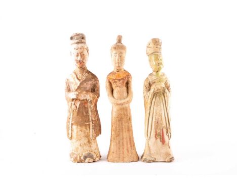 Three Chinese pottery figures, Tang dynasty, comprising a nobleman in hat and robe, with painted face, his robe and feet with