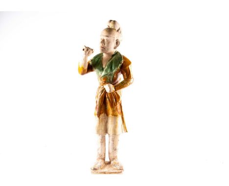 A Chinese Sancai glazed pottery figure of a Western groom, Tang dynasty, modelled standing, his face with a concentrated expr