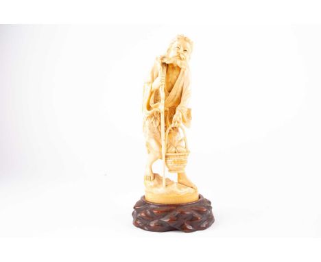 A Japanese carved ivory okimono of a man, Meiji period, wearing a robe with Artemesia leaves attached to the rear, carrying a