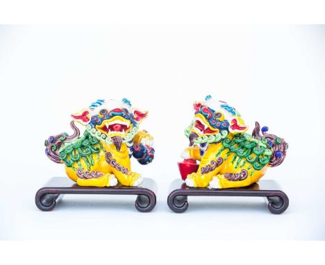 A pair of Chinese dogs of Fo, 20th century, each painted in bright enamels, one with a double gourd in its paw the other with