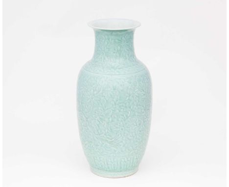A Chinese monochrome vase, 20th century, with low relief flowers growing from leafy branches over the ovoid body and neck, th
