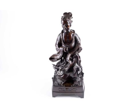 A Japanese bronze figure of a lady, Edo, 18th century, her hair combed back into a scroll held by an ornate hair clip, her lo