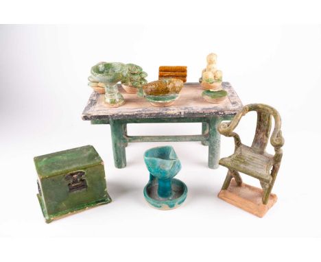 A Chinese earthenware feast, early Ming, a table set with various foods, including fruit, a carp and ingot bread, a horseshoe