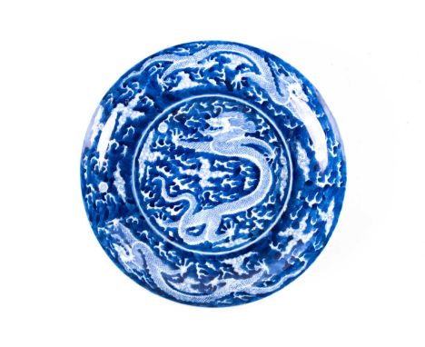 A Chinese porcelain blue and white dragon plate, of dished form, the cavetto with two further dragons amongst clouds, pseudo 