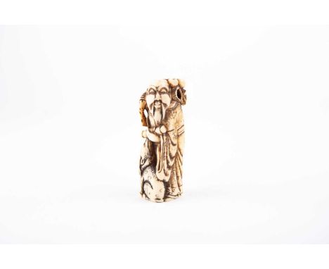 An early 19th century ivory netsuke, carved as Shoulao, holding a branch of peaches and a scroll, a deer looking up from his 