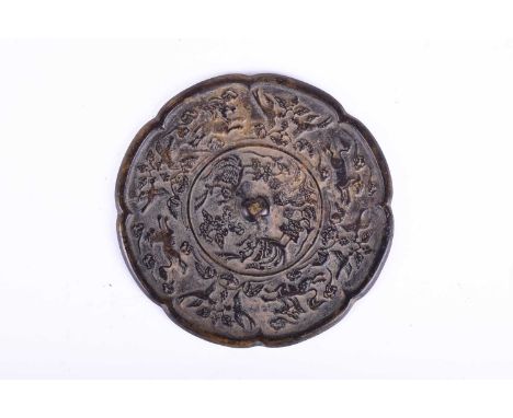 A Chinese bronze mirror, Tang Dynasty,of octagonal lobed form, cast with central pierced raised boss surrounded by two Feng a