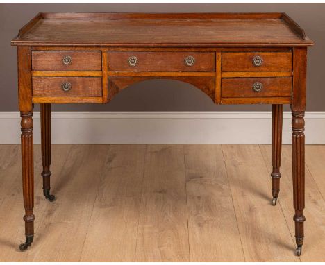 With a galleried back, five drawers with ring handles around a central recess and on Gillows style reeded legs terminating in